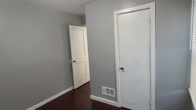 unfurnished bedroom featuring dark wood-type flooring and a closet