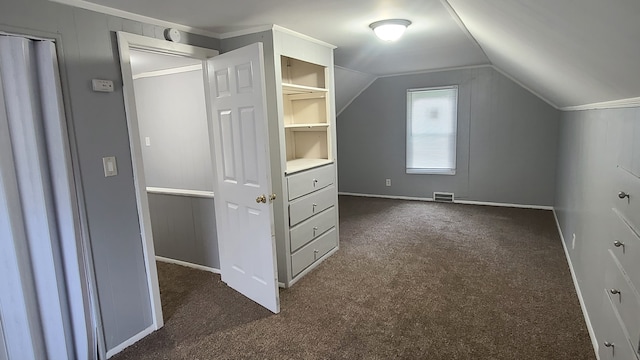 additional living space with vaulted ceiling and dark colored carpet