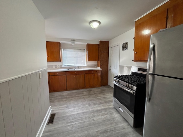 kitchen featuring appliances with stainless steel finishes, sink, and light hardwood / wood-style flooring