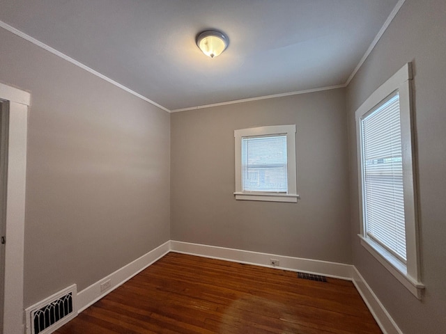 empty room featuring crown molding, dark wood-type flooring, and plenty of natural light