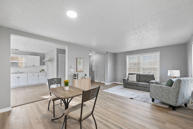 dining room featuring plenty of natural light, sink, a textured ceiling, and light hardwood / wood-style flooring