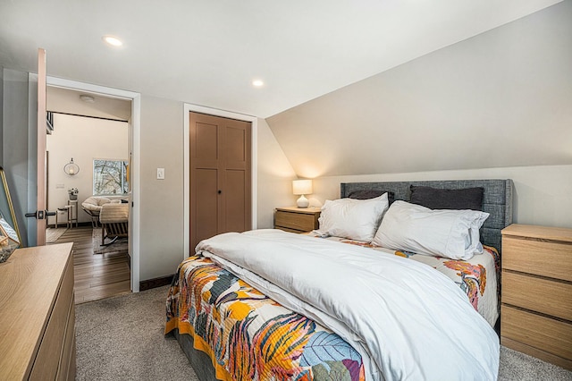 bedroom with vaulted ceiling, a closet, and dark colored carpet