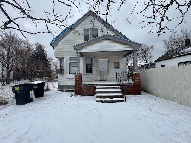 snow covered back of property with covered porch