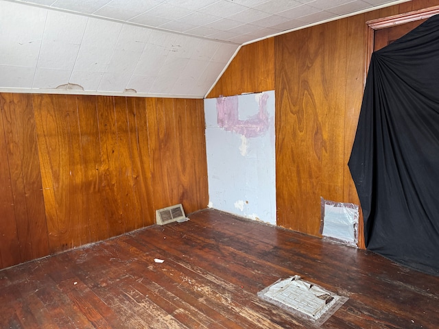 bonus room featuring dark hardwood / wood-style floors, lofted ceiling, and wooden walls