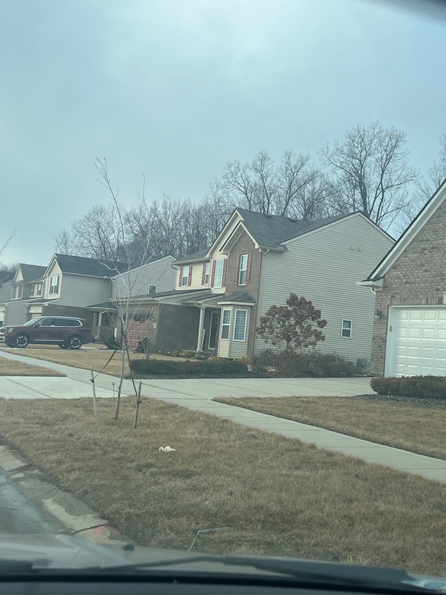 view of front of property featuring a garage, a residential view, concrete driveway, and brick siding