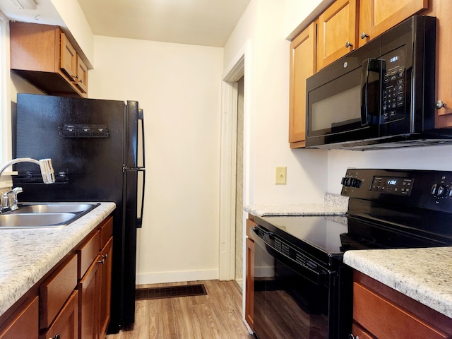 kitchen featuring sink, light hardwood / wood-style floors, and black appliances