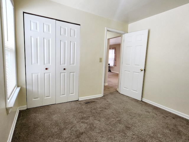 unfurnished bedroom with a closet and dark colored carpet