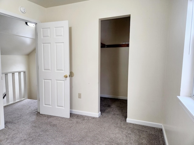 unfurnished bedroom with a walk in closet, a closet, and light carpet