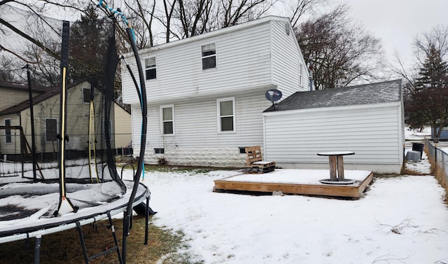 snow covered rear of property with a trampoline