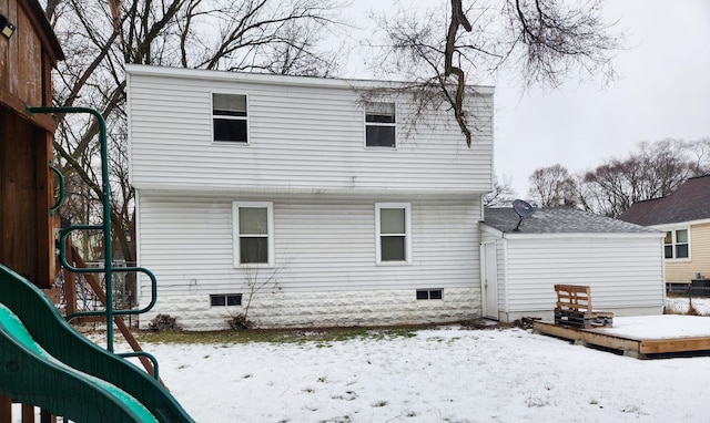 snow covered back of property with a playground