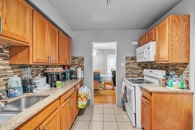 kitchen featuring light tile patterned flooring, tasteful backsplash, sink, light stone counters, and white appliances