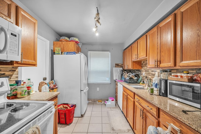 kitchen with light tile patterned flooring, sink, white appliances, light stone countertops, and backsplash