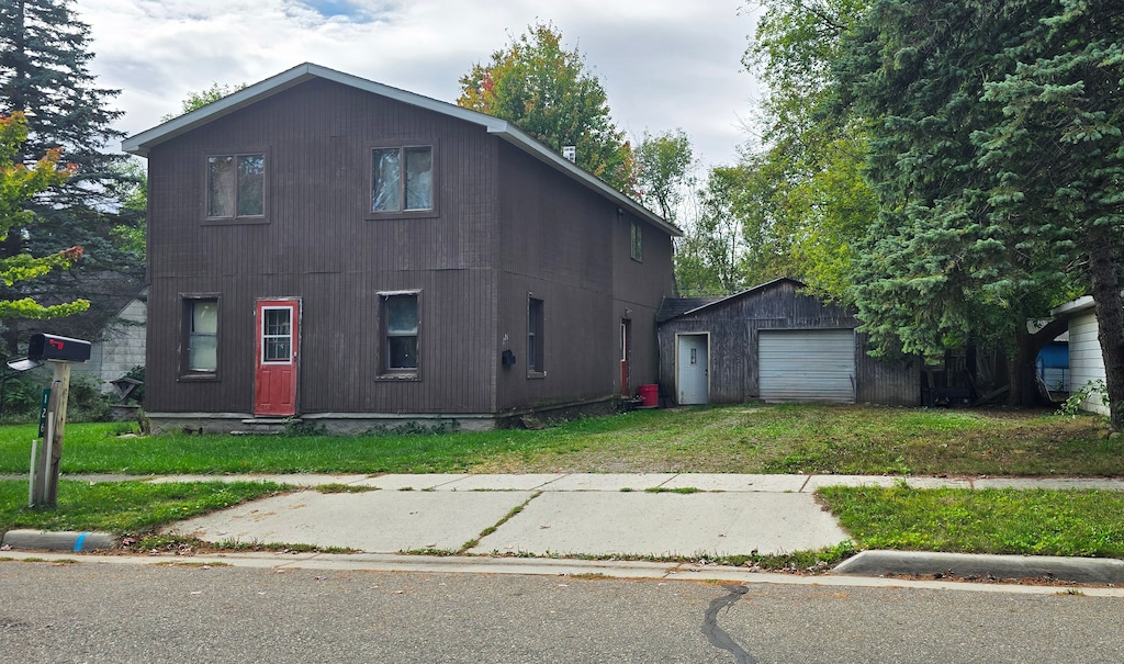 view of front of property featuring a garage, an outdoor structure, and a front yard