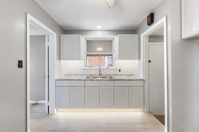 kitchen with white cabinetry, sink, light wood-type flooring, and decorative backsplash