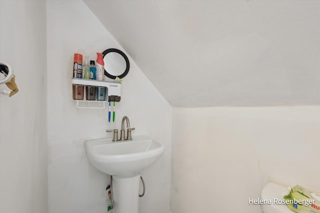 bathroom with lofted ceiling, sink, and toilet