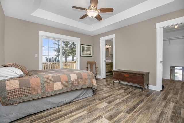 bedroom with dark hardwood / wood-style floors, access to outside, a raised ceiling, and ceiling fan