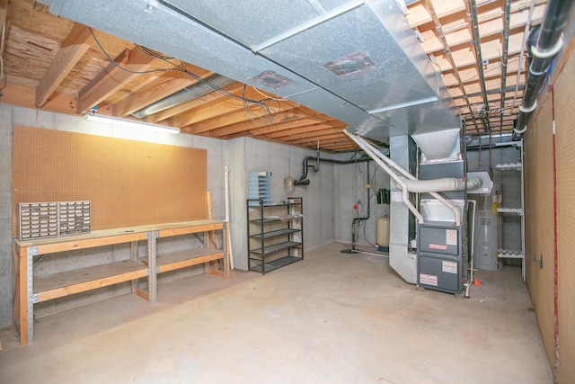 basement with heating unit, water heater, and a workshop area