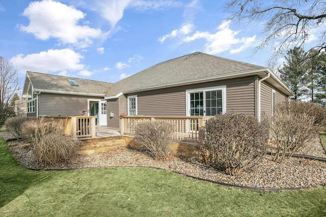 rear view of house featuring a deck and a lawn