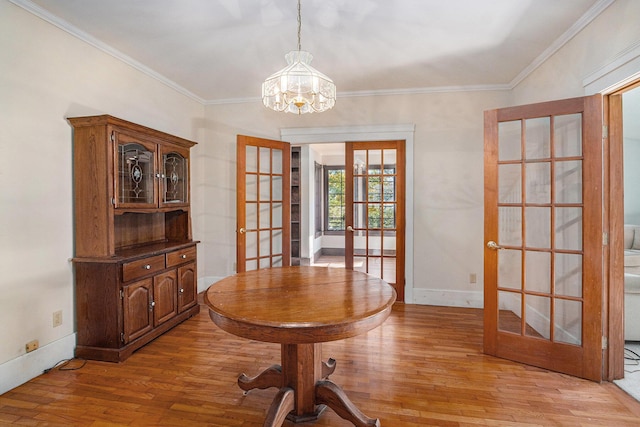 dining area featuring hardwood / wood-style floors, crown molding, french doors, and a chandelier