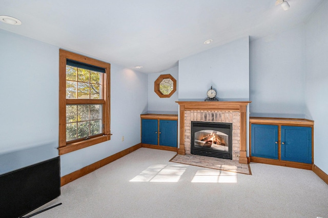 living room featuring a brick fireplace, vaulted ceiling, and light colored carpet