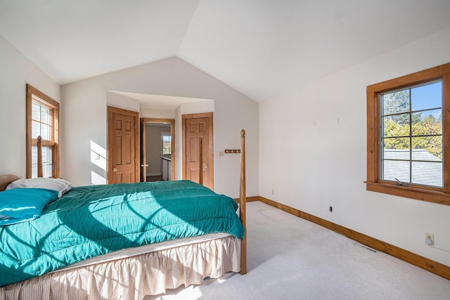 bedroom featuring light colored carpet, vaulted ceiling, and multiple windows