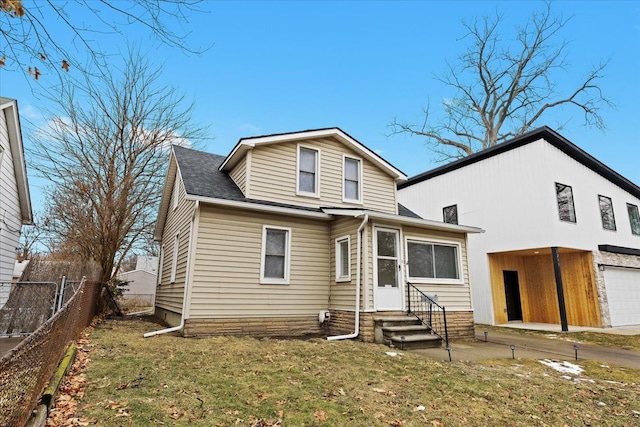 rear view of property featuring a garage and a lawn