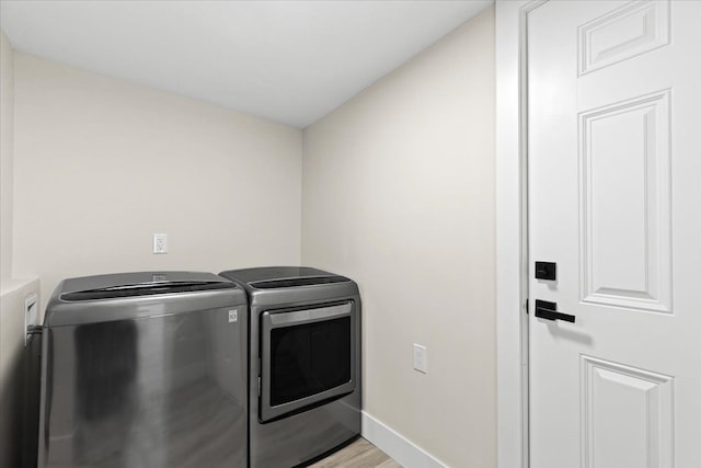 laundry room with washer and clothes dryer and light wood-type flooring