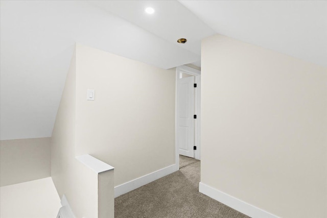 hall featuring vaulted ceiling and light colored carpet