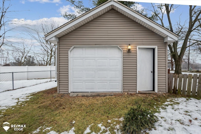 snow covered garage featuring a lawn