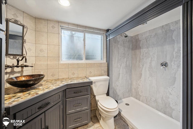 bathroom featuring tiled shower, toilet, tile walls, vanity, and backsplash