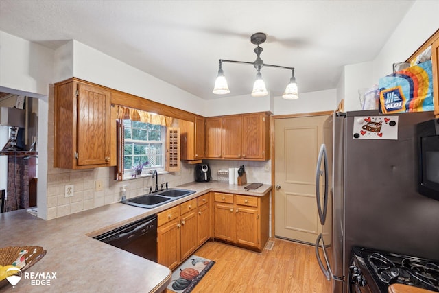 kitchen with stainless steel refrigerator, dishwasher, sink, decorative backsplash, and hanging light fixtures