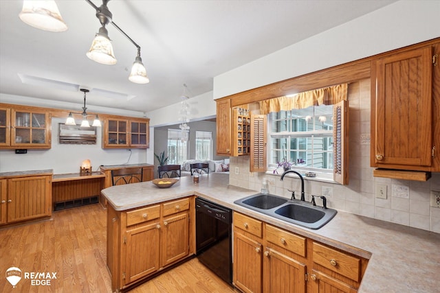 kitchen featuring sink, black dishwasher, decorative light fixtures, kitchen peninsula, and light wood-type flooring