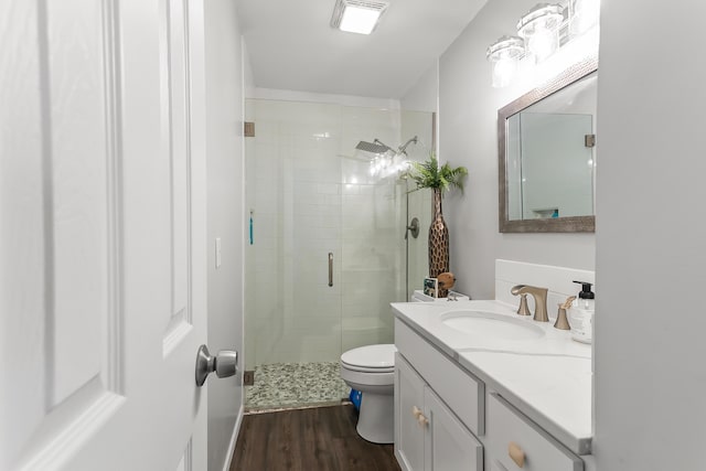 bathroom with vanity, hardwood / wood-style flooring, a shower with door, and toilet