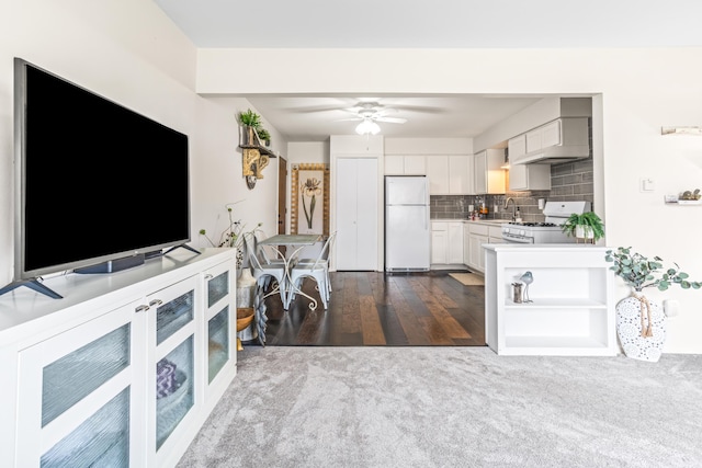 kitchen with white appliances, white cabinets, light countertops, ventilation hood, and decorative backsplash