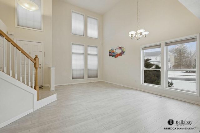 entrance foyer with plenty of natural light, high vaulted ceiling, a notable chandelier, and light hardwood / wood-style floors