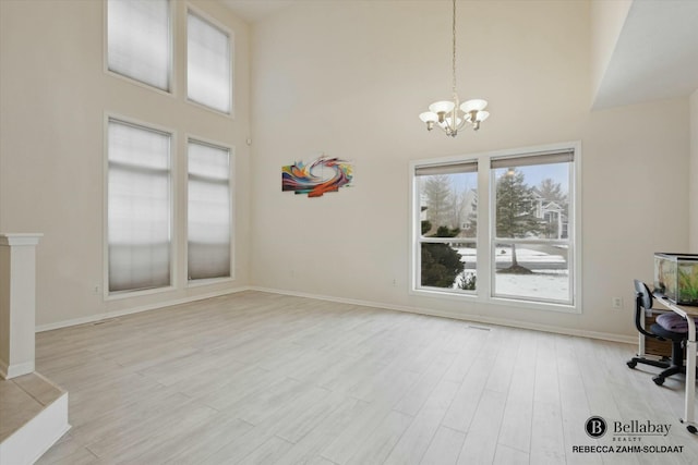 interior space with an inviting chandelier, light hardwood / wood-style flooring, and a high ceiling