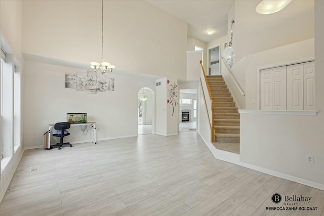 interior space with plenty of natural light, a towering ceiling, and light hardwood / wood-style floors