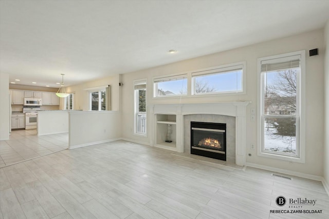 unfurnished living room featuring a tiled fireplace and light wood-type flooring