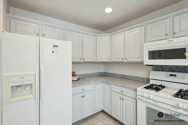 kitchen with white appliances, white cabinets, and light tile patterned flooring