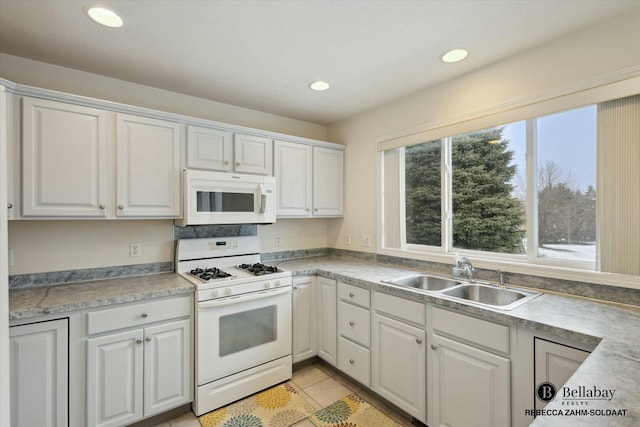 kitchen with sink, white appliances, light tile patterned floors, and white cabinets