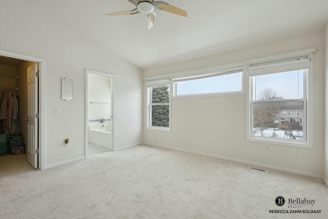 unfurnished bedroom featuring ensuite bathroom, lofted ceiling, a walk in closet, light carpet, and a closet