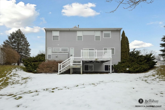 snow covered rear of property with a deck