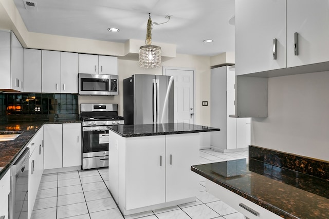 kitchen featuring backsplash, stainless steel appliances, white cabinets, and a kitchen island