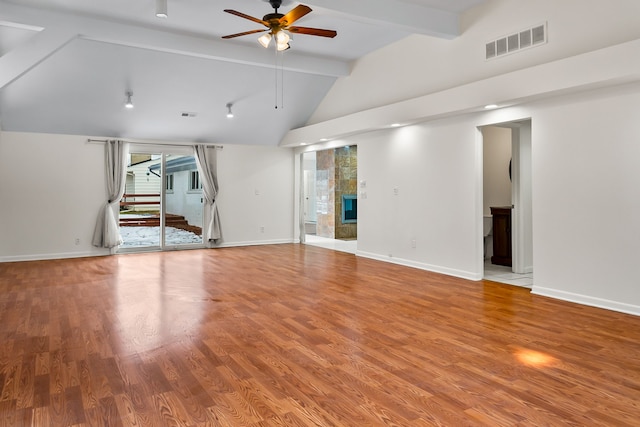 unfurnished living room featuring a tiled fireplace, hardwood / wood-style flooring, vaulted ceiling with beams, and ceiling fan