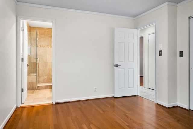 unfurnished bedroom with crown molding, connected bathroom, and hardwood / wood-style floors