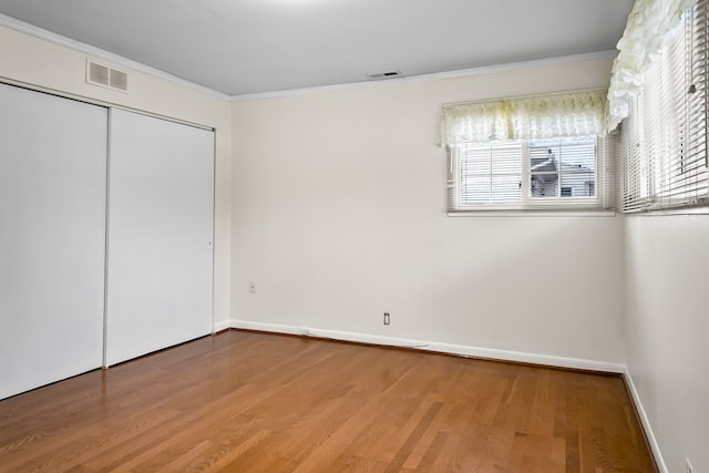 unfurnished bedroom with ornamental molding, wood-type flooring, and a closet