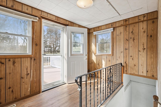 entryway with lofted ceiling, wooden walls, and light hardwood / wood-style flooring