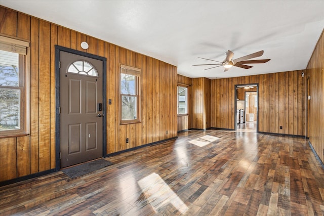 foyer with ceiling fan, a healthy amount of sunlight, wooden walls, and dark hardwood / wood-style flooring