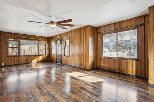 empty room featuring ceiling fan, wooden walls, and dark hardwood / wood-style flooring