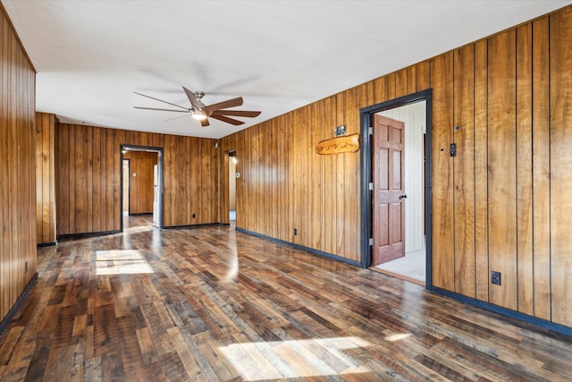 spare room featuring wooden walls, ceiling fan, and dark hardwood / wood-style flooring